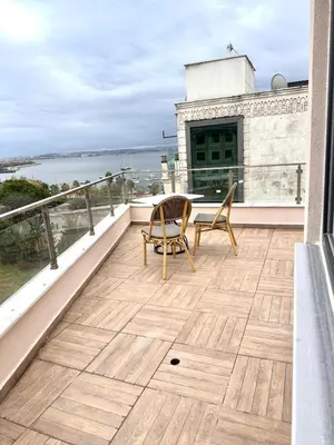 a balcony with a table and chairs on top of a building at Şeker Apartments in Tuzla