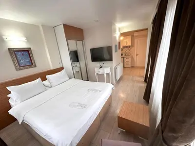 a bedroom with a white bed and a television at Şeker Apartments in Tuzla