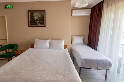 a room with two beds and a chair and a window at Lion Stone Hotel in Istanbul