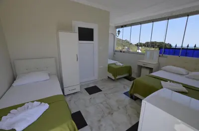 a bedroom with two beds and a desk and a window at Grand Şakar Otel in Marmara