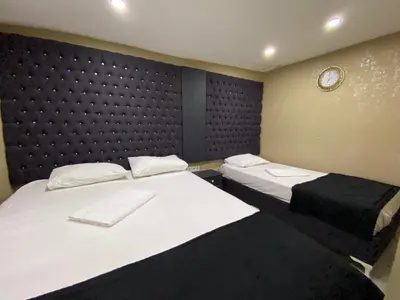 a room with two beds and a black padded wall at Orange Airport Hotel in Istanbul