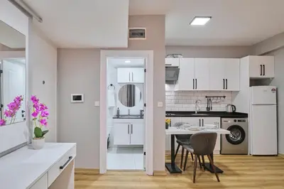 a kitchen with white cabinets and a table and chairs at Ulker Apartments in Istanbul