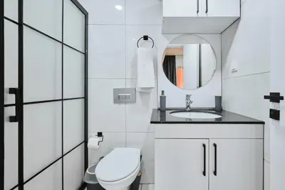 a white bathroom with a toilet and a mirror at Ulker Apartments in Istanbul