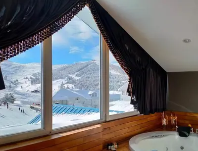 a large window in a bathroom with a tub and a view at Bof Hotels Uludağ Ski&Luxury Resort All Inclusive in Uludag