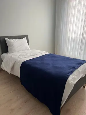 a bed with a blue blanket and a window at Bediroğlu Airport Apart in Arnavutköy