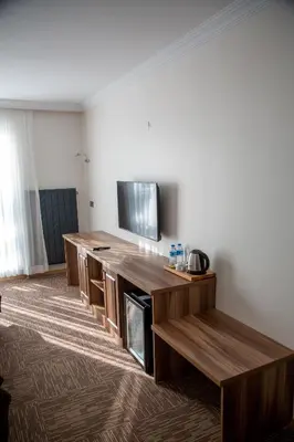 a room with a tv and a wooden entertainment center at The Life Nest Hotel in Saray