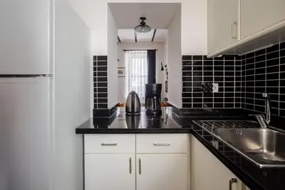 a kitchen with white cabinets and a sink and black tiles at Authentic Galata Tower Central 2BD2Bath Home #411 in Istanbul