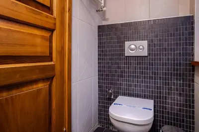 a bathroom with a toilet and a black tiled wall at Galata Tower 2BD2Bath Authentic Gem! #412 in Istanbul