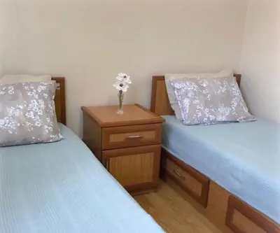a bedroom with two beds and a vase of flowers on a table at Akademik Pansiyon in Istanbul