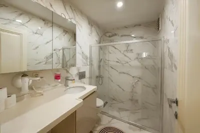 a white bathroom with a shower and a sink at Gold Suit - Bakırköy City Center in Istanbul