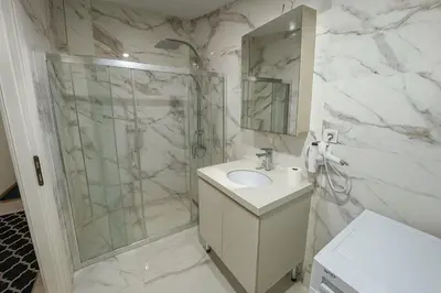 a white bathroom with a shower and a sink at Gold Suit - Bakırköy City Center in Istanbul