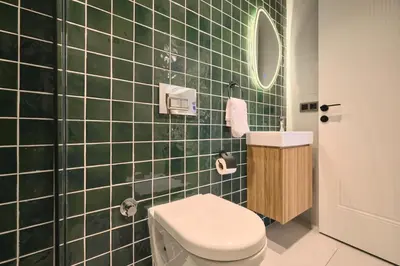 a green tiled bathroom with a toilet and a sink at BSY Flats Well Decorated Modern Apartments With 2BR, 3BR Options in Istanbul