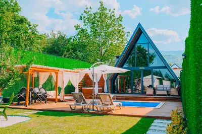a house with a pool and a patio with chairs and an umbrella at Melodi Bungalov Sapanca in Sakarya