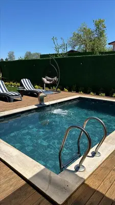 a swimming pool with a faucet and two lawn chairs at Melodi Bungalov Sapanca in Sakarya
