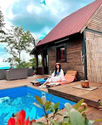 a woman sitting on a deck next to a house at Sapanca Balkaya Bungalov Dağ evi in Sapanca