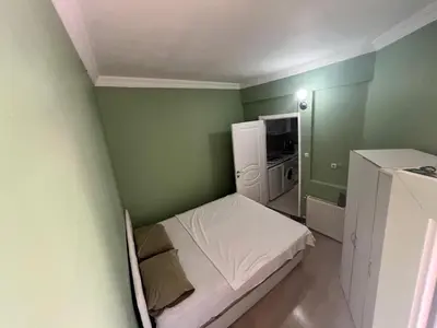 a small bedroom with a bed in a green wall at Meryy Home in Istanbul