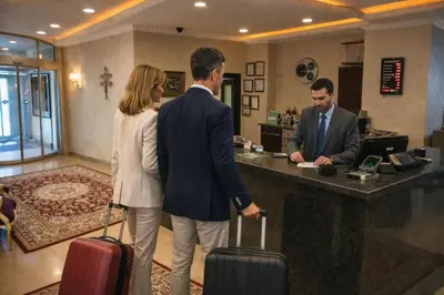 a man and a woman standing at a counter with luggage at Akgün Hotel Laleli Istanbul in Istanbul