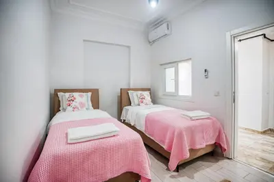 a bedroom with two beds with pink sheets and a mirror at HANLAR Apart in Istanbul