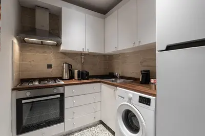 a kitchen with white cabinets and a washer and dryer at Renovated Flat near Tram All Rooms AC in Istanbul