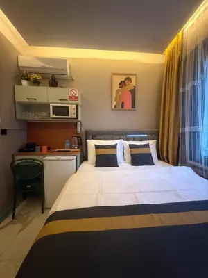a bedroom with a large bed and a kitchen at Warm cozy studio 8 min by metro station in Istanbul