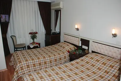 a hotel room with two beds with a plaid blanket at Hotel Grand Mark in Istanbul