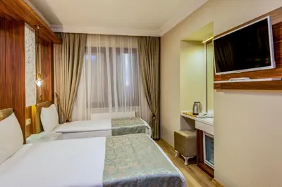 a hotel room with two beds and a television at Kupeli Hotel in Istanbul