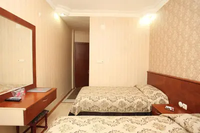 a bedroom with two beds and a dresser and a mirror at Turvan Hotel in Istanbul
