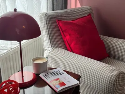 a lamp on a table next to a chair with a red pillow at Stylish Apartment 3 Min to Metro in Istanbul