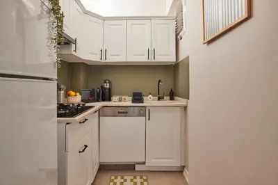 a white kitchen with white cabinets and a sink at 2BR Modern Flat in Nişantaşı 3 Min to Metro Full AC in Istanbul