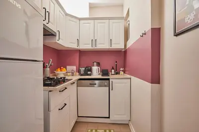 a small kitchen with white cabinets and pink walls at Modern 2BR in Nisantasi Area Balconies & AC in Istanbul