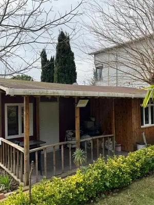 a house with a porch with a tree in the background at Ciğ Bungalov Airport in Arnavutköy