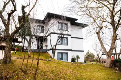 a white house on top of a hill with trees at Terrazzo Sapanca - Isıtmalı Havuzlu Villa Süha Fazlı in Sapanca