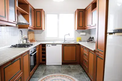 a kitchen with wooden cabinets and a white dishwasher at Terrazzo Sapanca - Isıtmalı Havuzlu Villa Süha Fazlı in Sapanca