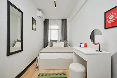 a white bedroom with a bed and a mirror at Stylish 2BR in Central Istanbul 3-Min to Metro in Istanbul