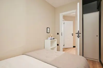 a white bedroom with a white bed and a door at Heart of the City 3 Min to Metro 2BR AC in Istanbul