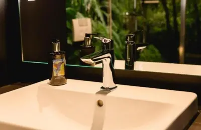 a bathroom sink with a faucet and a mirror at White garden in Tuzla