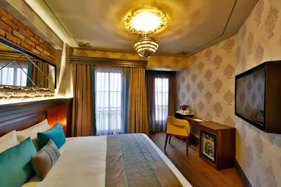 a bedroom with a bed and a desk and a television at Sanat Boutique Hotel Pera in Istanbul