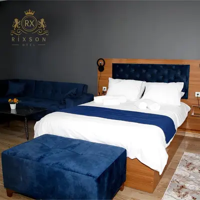 a bedroom with a large bed and a blue ottoman at Riwaner Hotel in Avcılar
