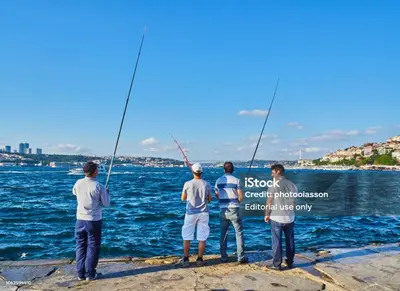 a group of men standing on a dock with fishing rods at Sağlam Apartments 1 in Istanbul