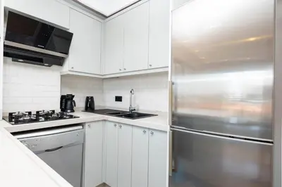 a kitchen with white cabinets and a stainless steel refrigerator at Sea View Two-Bedroom Suite in Managed Residence - Parking and Elevator in Istanbul