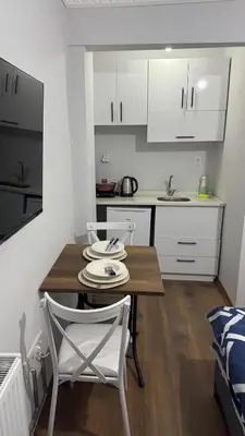 a small kitchen with a wooden table and white cabinets at balatlifesuites in Istanbul