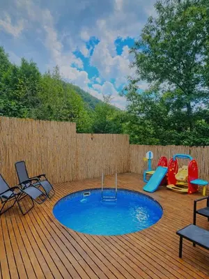 a pool on a wooden deck with chairs and a playground at Alyüz Bungalov in Sapanca