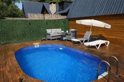 a swimming pool with an umbrella and two chairs at Alyüz Bungalov in Sapanca