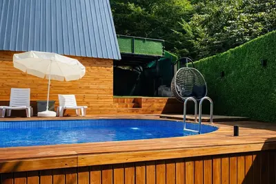 a pool with a fan and an umbrella on a wooden deck at Alyüz Bungalov in Sapanca