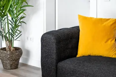 a gray couch with a yellow pillow next to a plant at Trendy 2BD Cozy Modern Bebek Home! #415 in Istanbul