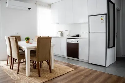 a white kitchen with a table and a refrigerator at Trendy 2BD Cozy Modern Bebek Home! #415 in Istanbul
