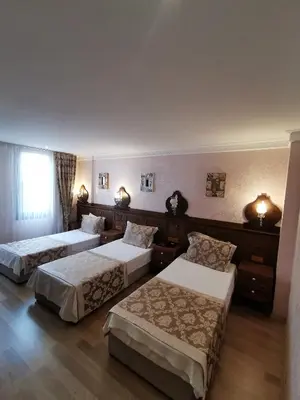 a hotel room with three beds and a window at Perapolis Hotel in Istanbul