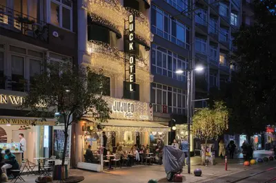 a street with people sitting outside a store at night at Duck Hotel in Istanbul