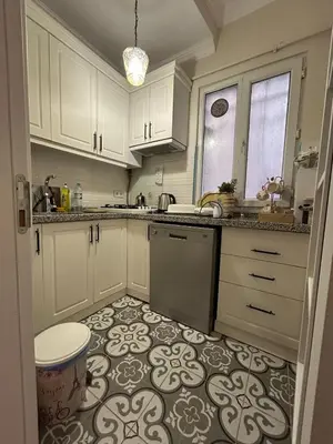 a kitchen with white cabinets and a tile floor at Bohemian Antique House in Colorful Balat in Istanbul