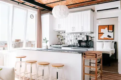 a kitchen with white cabinets and stools in front of a counter at Stunning City View Luxury Flat by Galata Metro in Istanbul